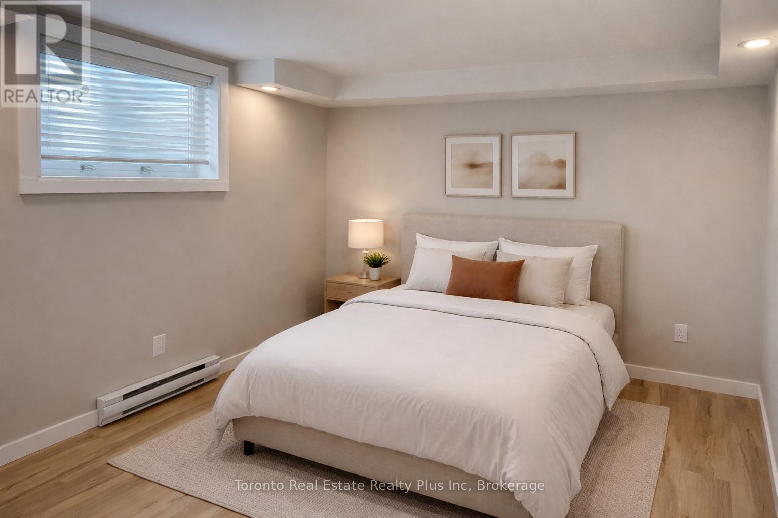 A bedroom with a white bed and a window with blinds.