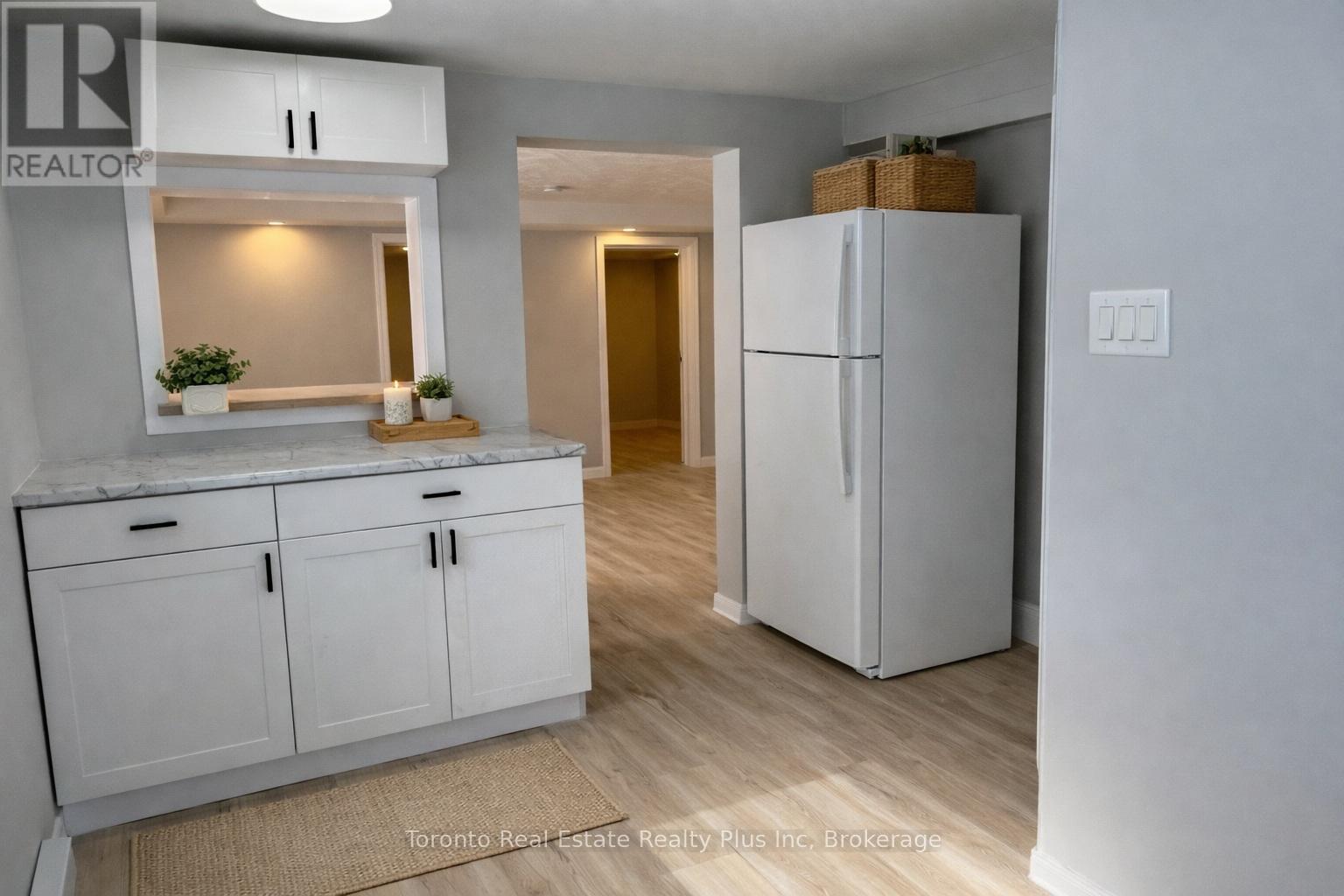 A kitchen with white cabinets and a refrigerator.