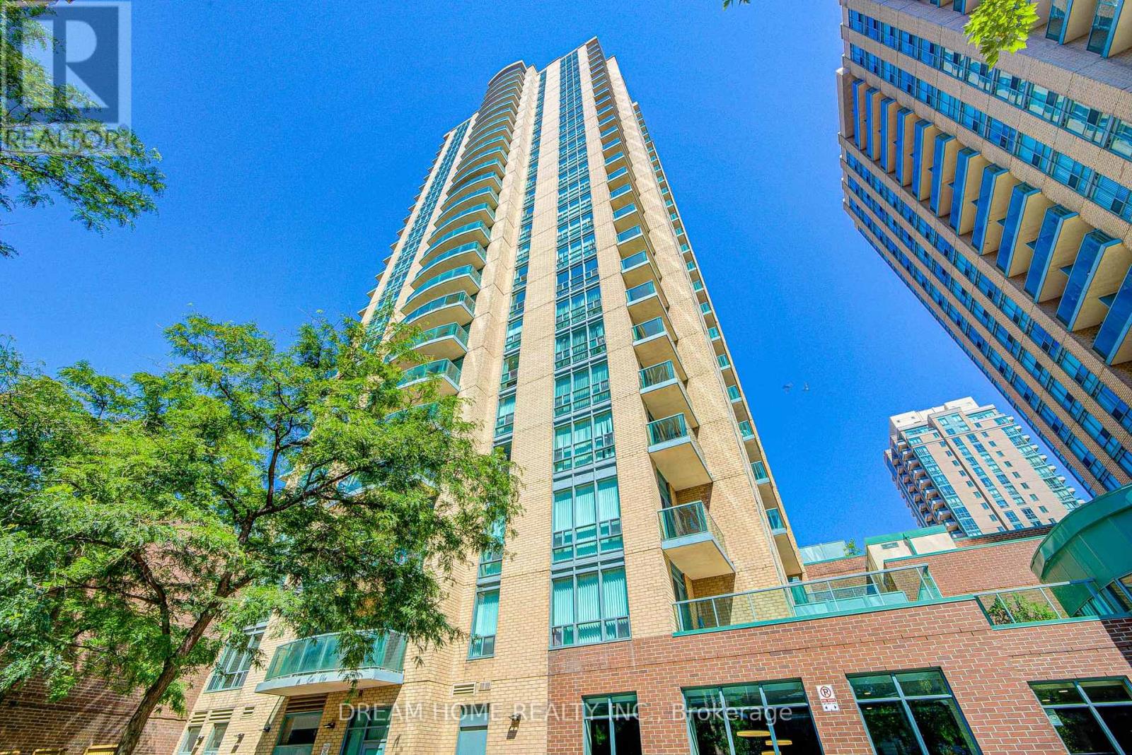 A tall building with a glass facade stands in front of a blue sky.