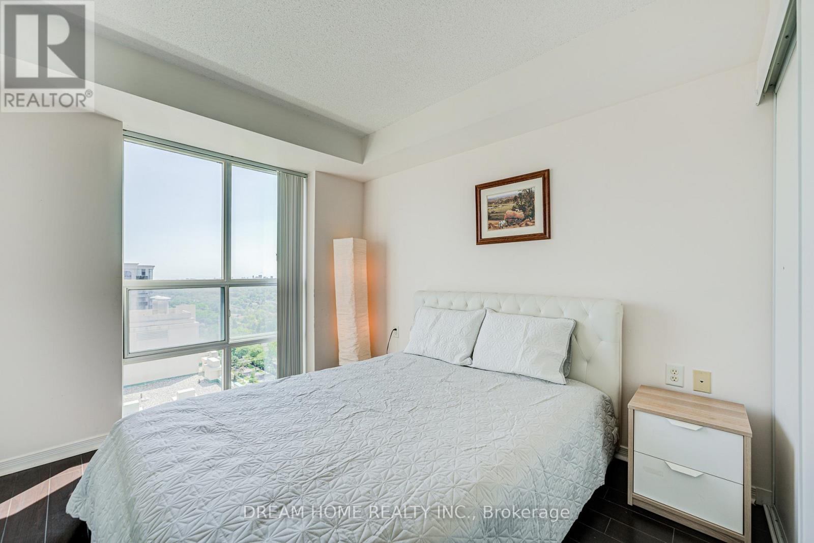 A bedroom with a large bed and a window overlooking a cityscape.
