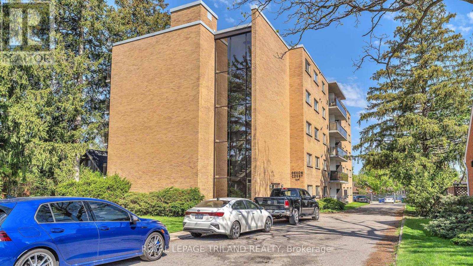 A blue car is parked in front of a brick building with a sign that reads "LEPAGE TRILAND REALTY Brokerage.".
