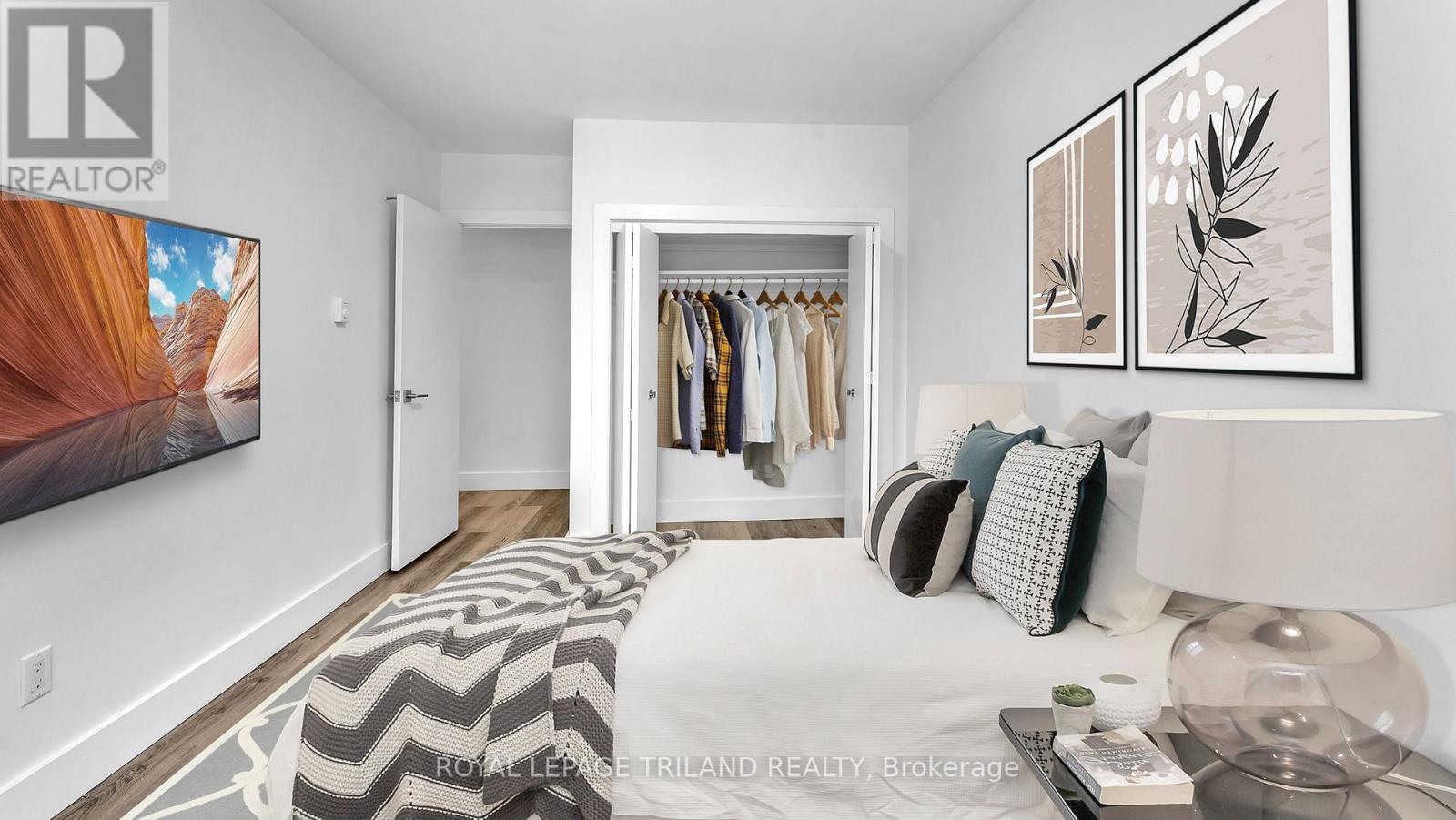 A bedroom with a bed, a clothing rack, and a painting on the wall.