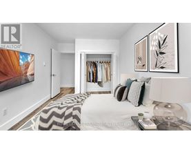 A bedroom with a bed, a clothing rack, and a painting on the wall.