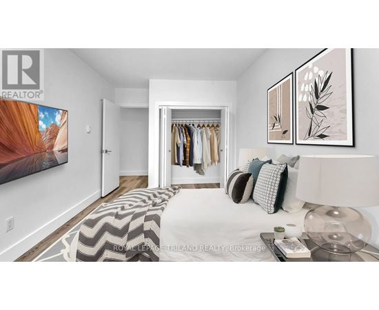 A bedroom with a bed, a clothing rack, and a painting on the wall.