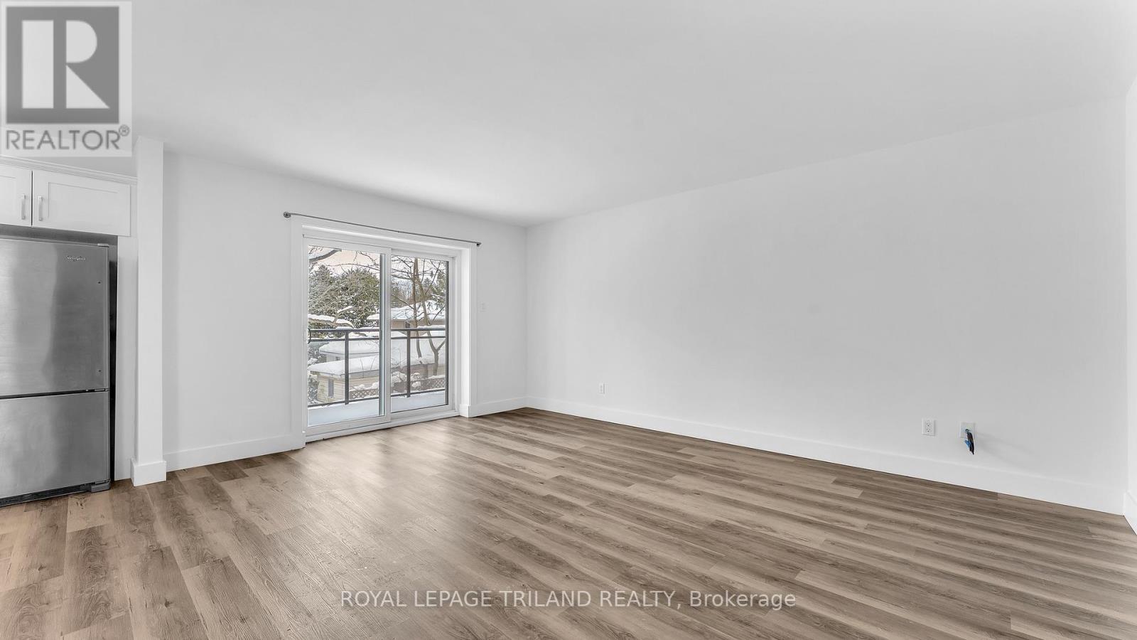 A spacious room with wooden flooring and a large window.