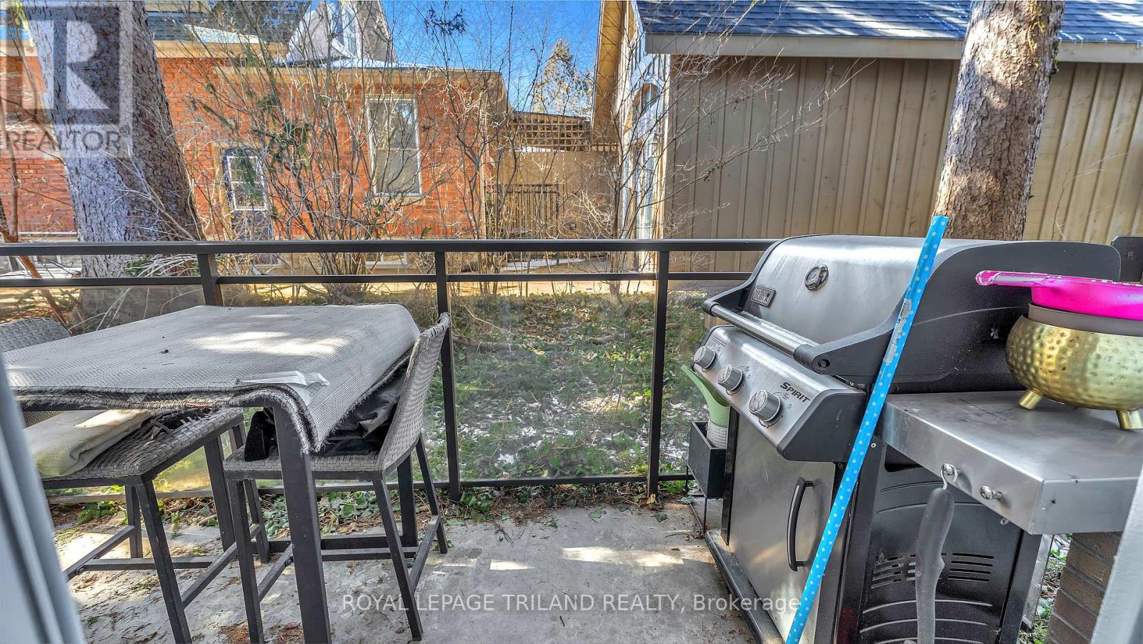 A BBQ grill is on a balcony with a table and chairs.