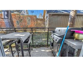 A BBQ grill is on a balcony with a table and chairs.