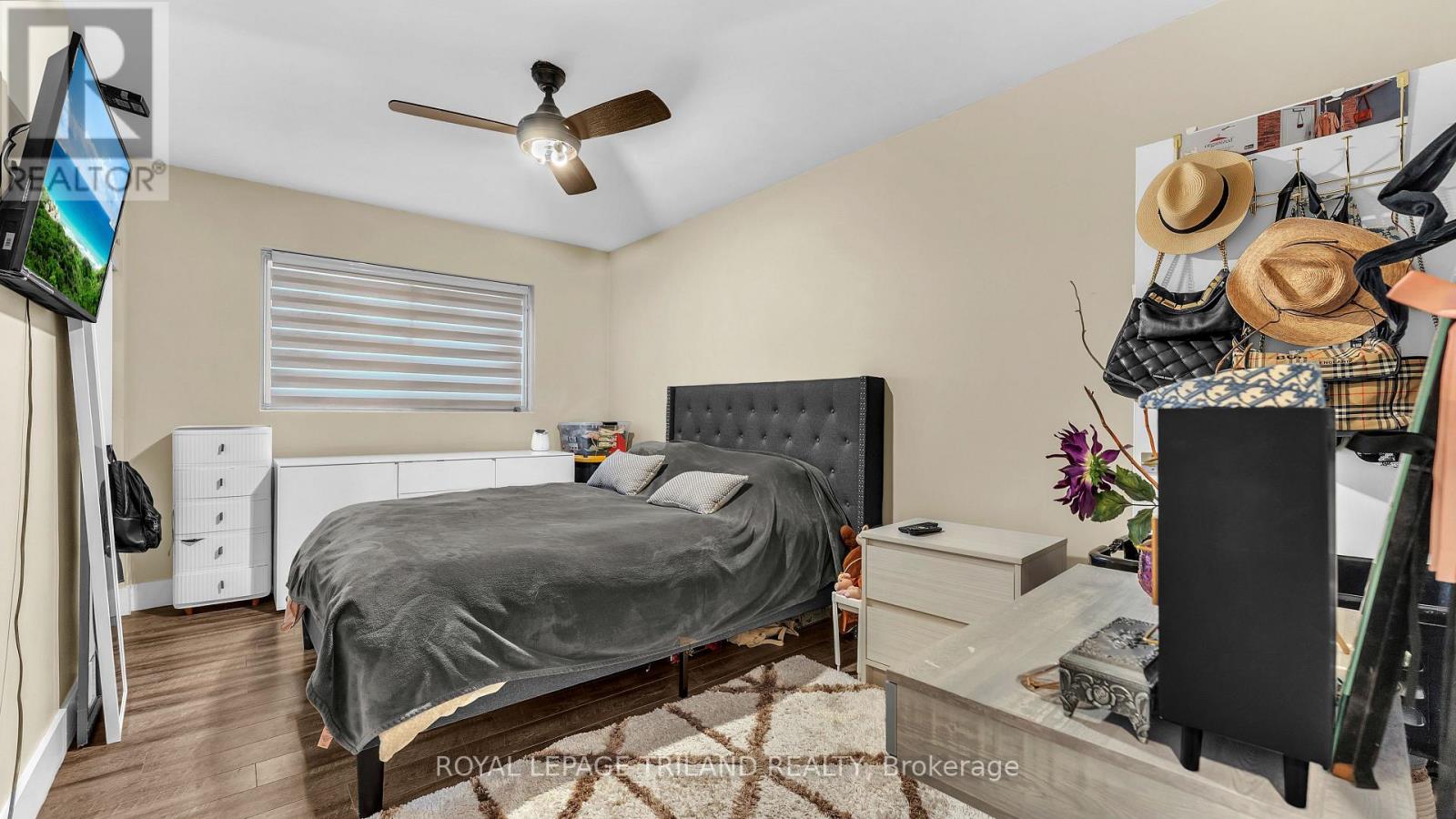 A bedroom with a bed, dresser, and ceiling fan.
