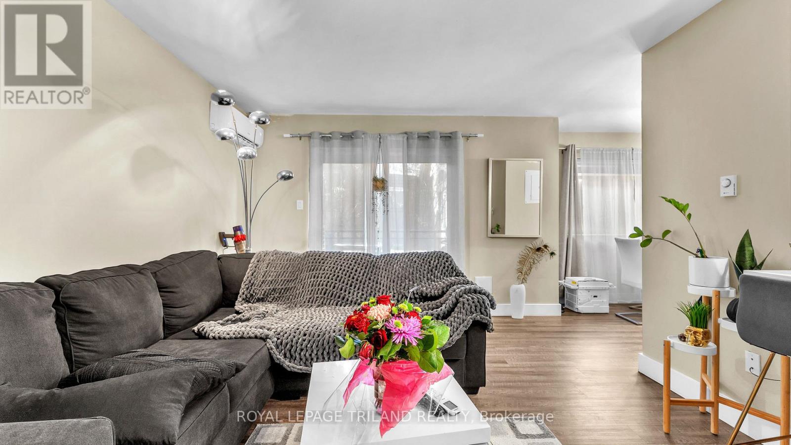 A living room with a grey sofa and a coffee table with a vase of flowers on it.