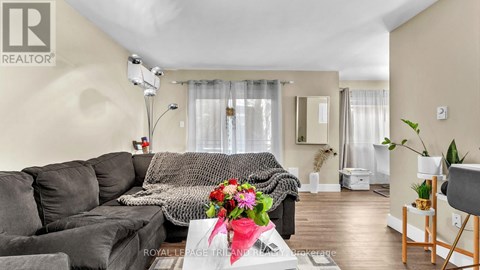 A living room with a grey sofa and a coffee table with a vase of flowers on it.