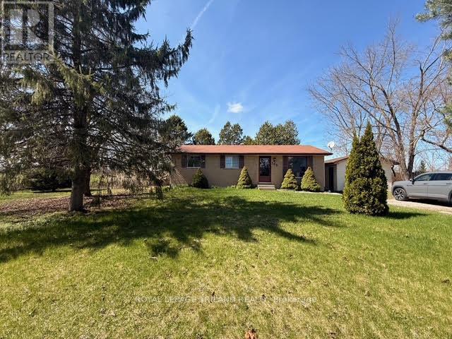 A house with a brown roof and a green lawn in front.