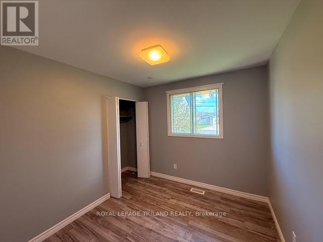 A room with a wooden floor and a window with a view of trees outside.