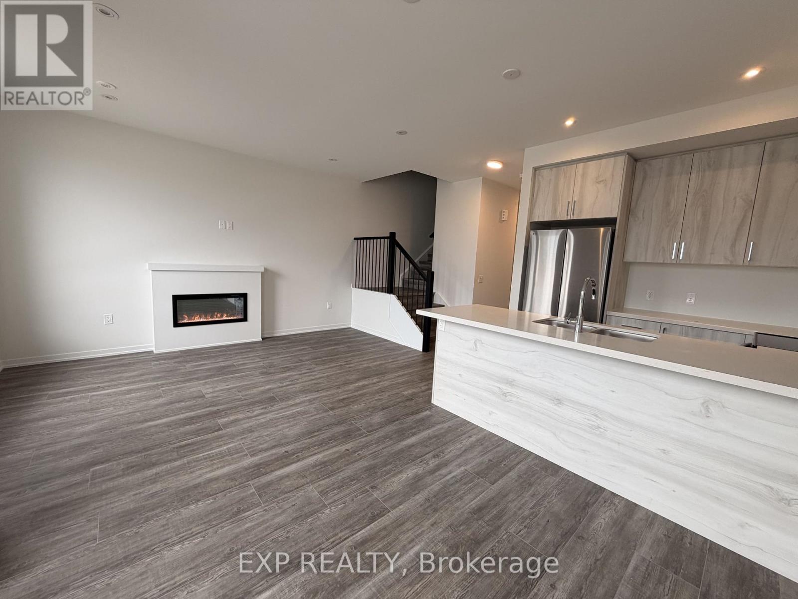 A spacious room with a fireplace and a staircase.