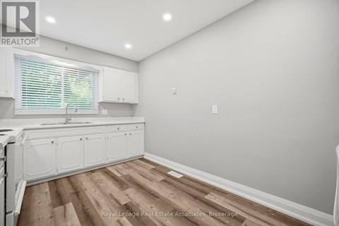 A kitchen with white cabinets and a wooden floor.