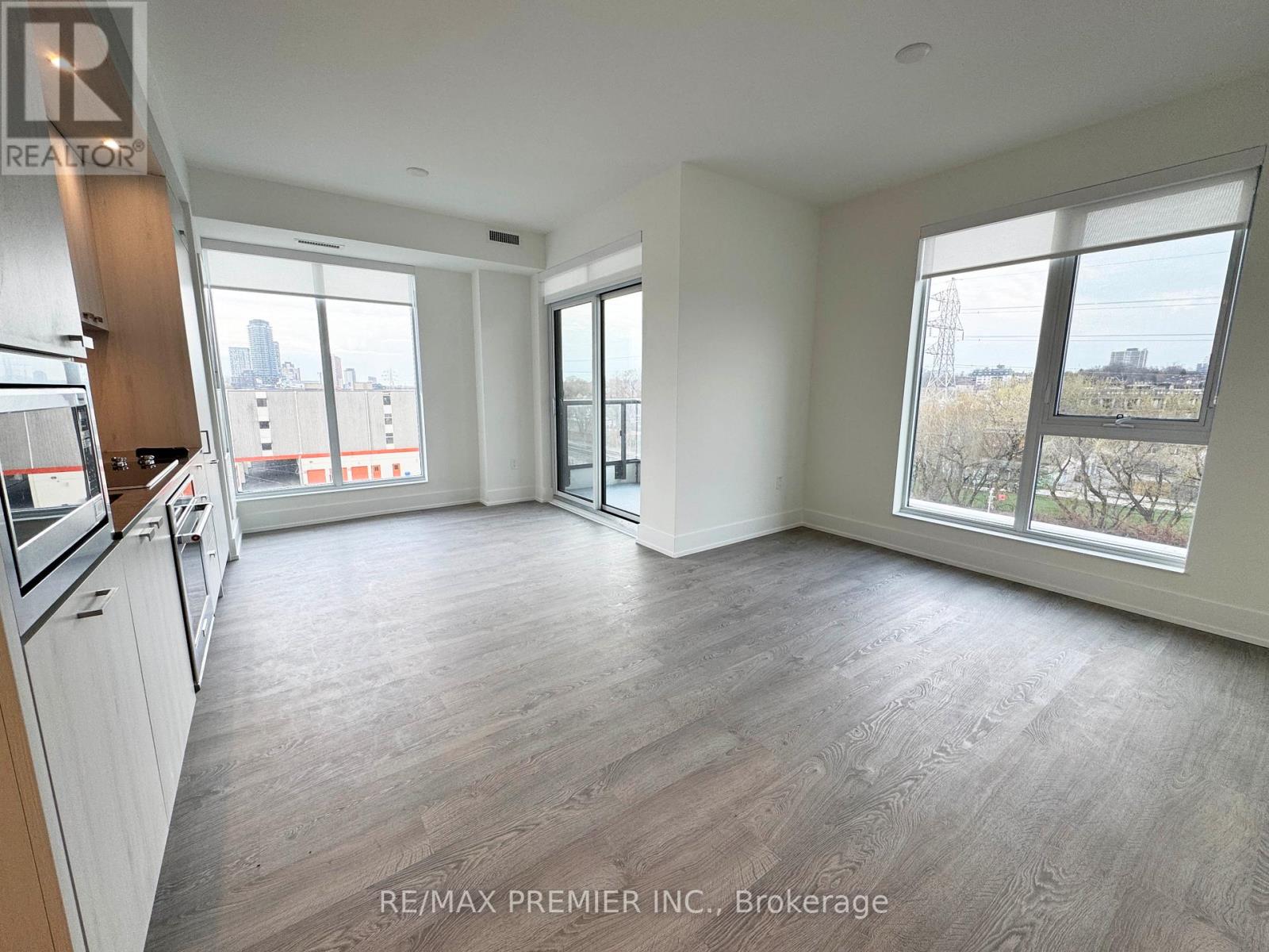 A spacious, empty room with wood flooring and large windows.