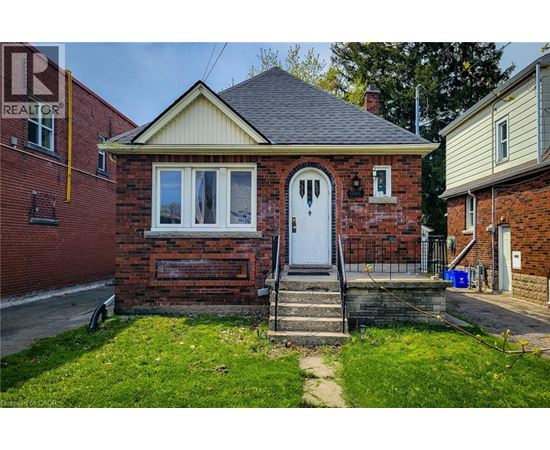A small red brick house with a white door and a small porch.