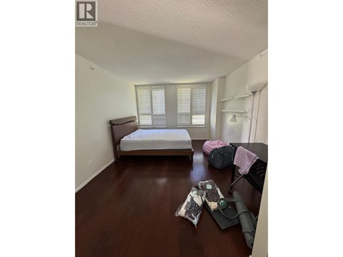 A bedroom with a bed, a table with items on it, and a window with blinds.