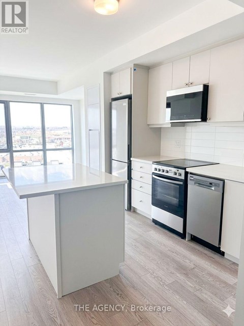 A modern kitchen with a large island and stainless steel appliances.