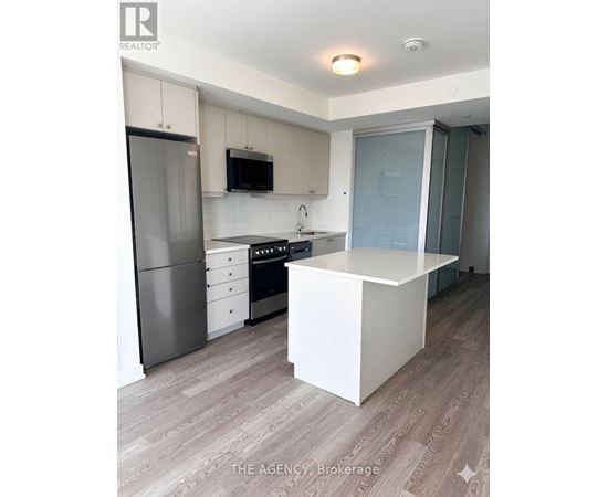 A kitchen with a refrigerator, microwave, oven, and sink.