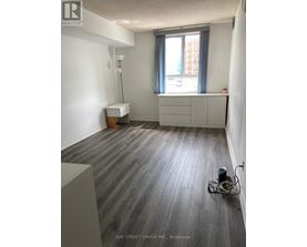 A room with a grey floor and a window with a grey curtain.