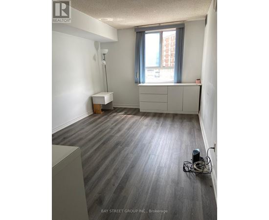 A room with a grey floor and a window with a grey curtain.