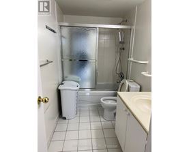 A small white bathroom with a toilet, sink, and shower.