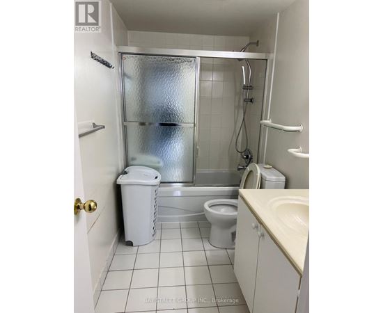 A small white bathroom with a toilet, sink, and shower.