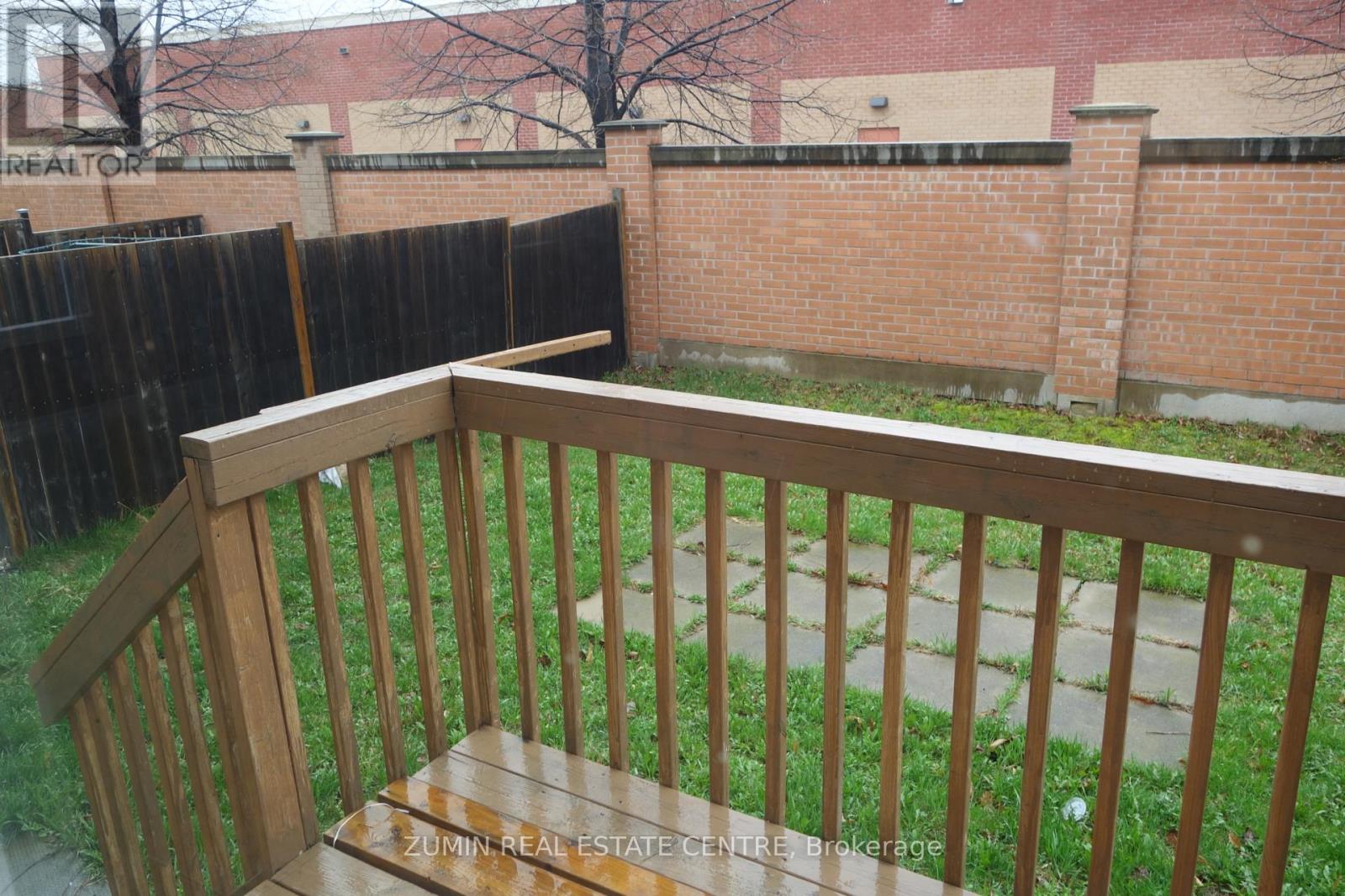 A wooden deck with a railing overlooking a grassy area.