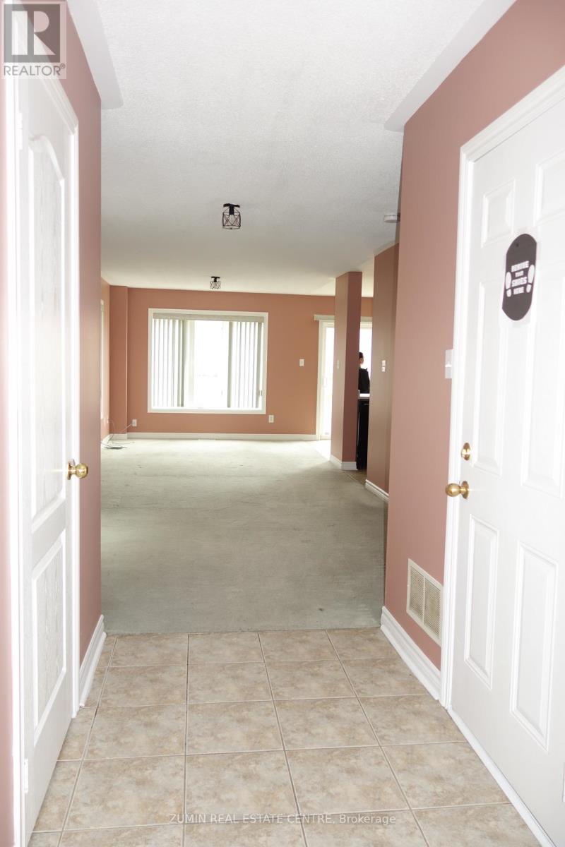 A hallway with a white door on the right and a window with blinds on the left.