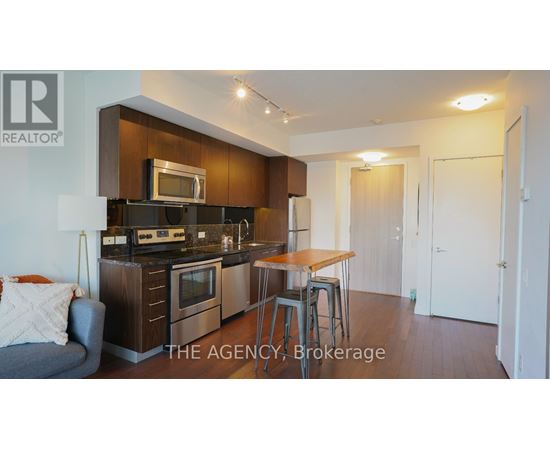 A modern kitchen with dark wood cabinets and stainless steel appliances.