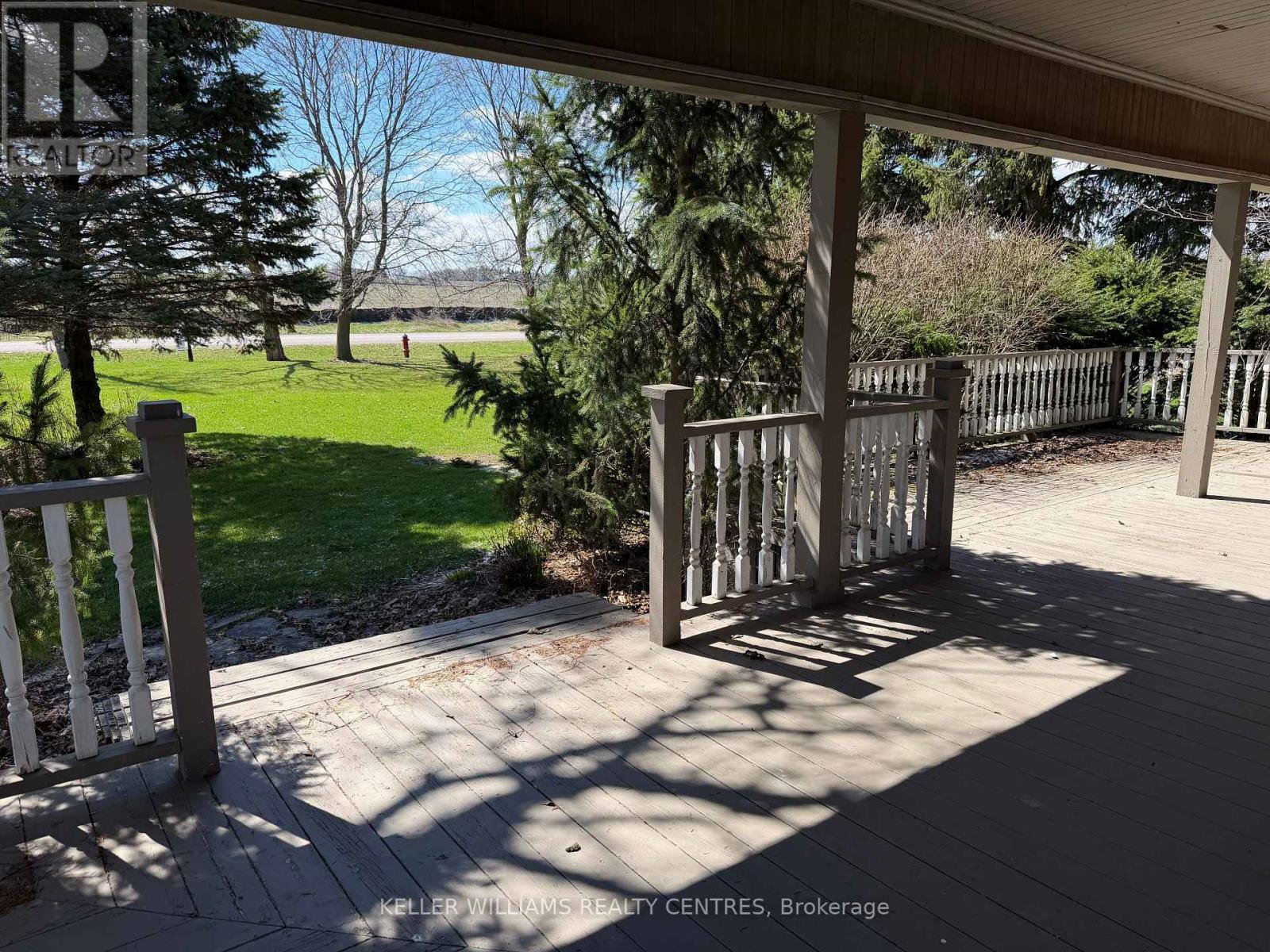 A view from a porch looking out to a grassy field.