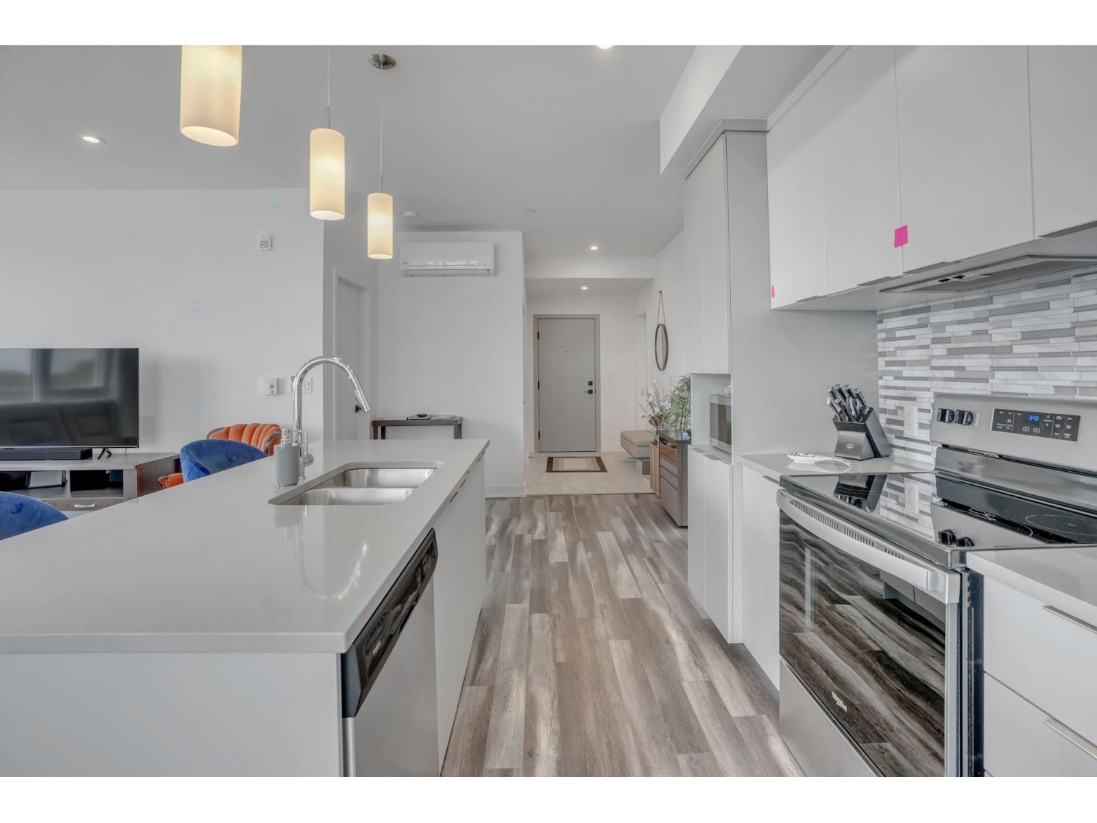 A modern kitchen with white cabinets and a wooden floor.