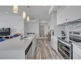 A modern kitchen with white cabinets and a wooden floor.