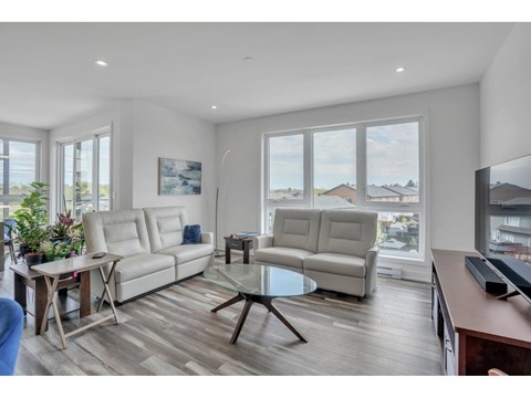 A living room with a white couch and a glass table.