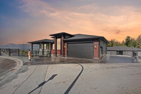 A building with a black roof and a red door is surrounded by a black fence.