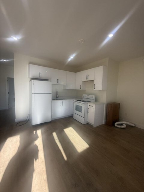 A kitchen with white appliances and wooden floors.