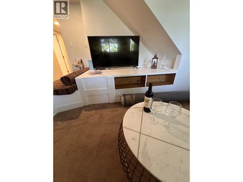 A living room with a television and a table with a bottle of wine on it.