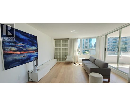 A living room with a large painting on the wall and a couch.