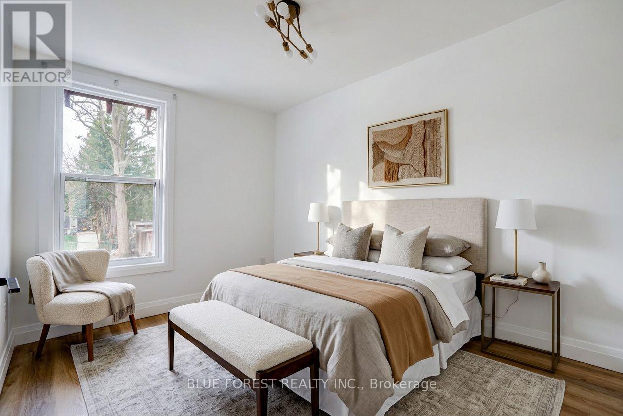 A bedroom with a bed, chair, and window.