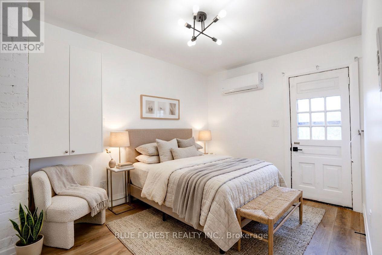 A bedroom with a bed, chair, and a plant.