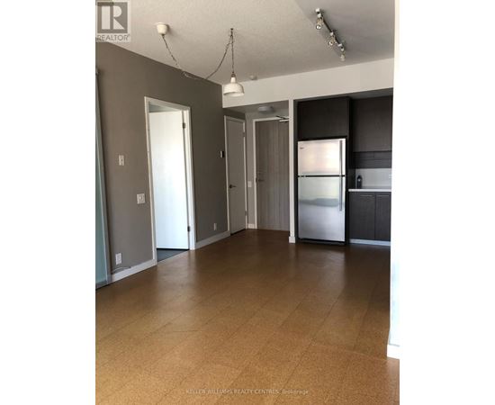 A spacious kitchen with a refrigerator, cabinets, and a countertop.