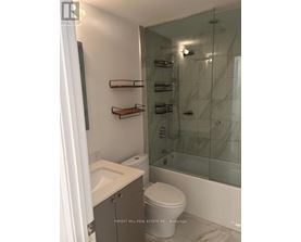 A white toilet sits in a bathroom with a glass shower stall.