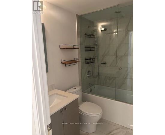 A white toilet sits in a bathroom with a glass shower stall.