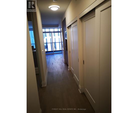 A hallway with doors on both sides and a window in the distance.