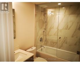 A bathroom with marble tiles and a glass shower stall.
