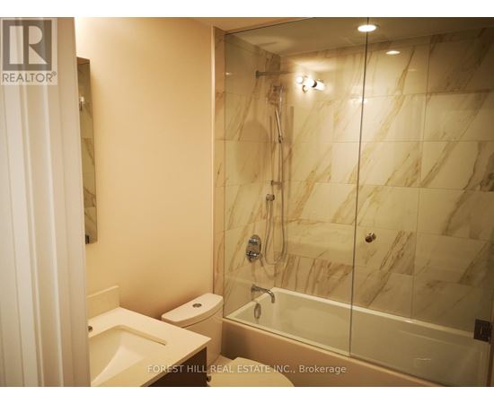 A bathroom with marble tiles and a glass shower stall.