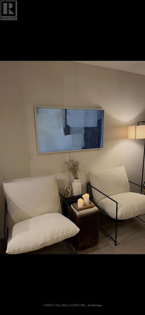 A living room with a couch, a chair, and a table with a vase and candles on it.