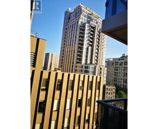 A tall building with many windows stands in front of a blue sky.