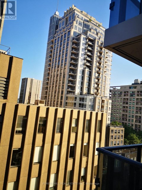 A tall building with many windows stands in front of a blue sky.