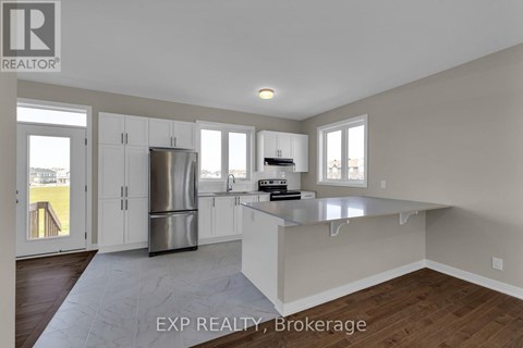 A kitchen with white cabinets and a stainless steel refrigerator.